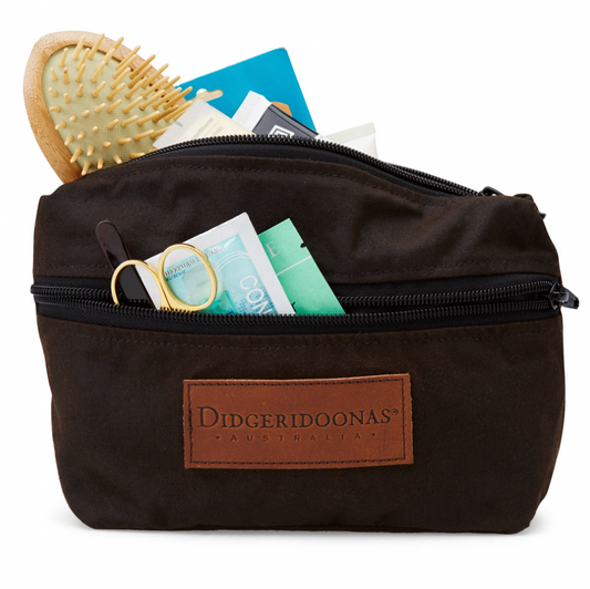 A brown shaving bag made of oilskin with a drawstring closure, containing various personal care items.